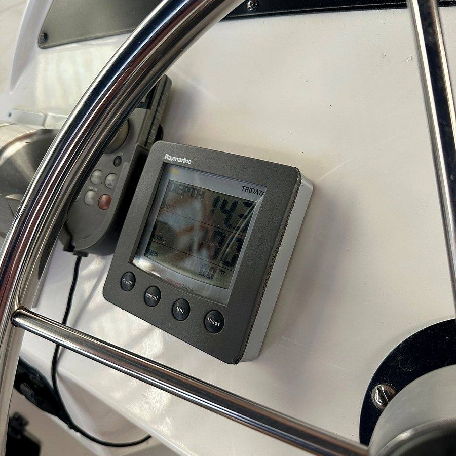 A small instrument display mounted on a white pedestal behind a stainless wheel